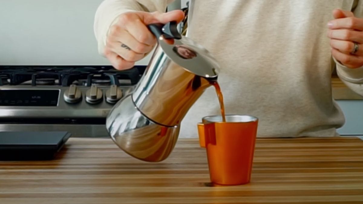 pouring coffee from The Luxhaus Moka Pot to the red cup 