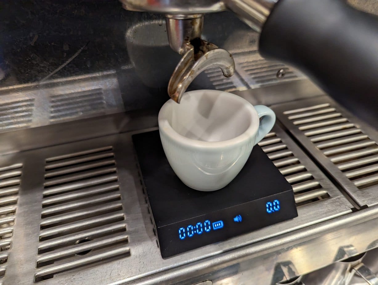 White ceramic cup on the Black Mirror Nano scales On Drip Tray