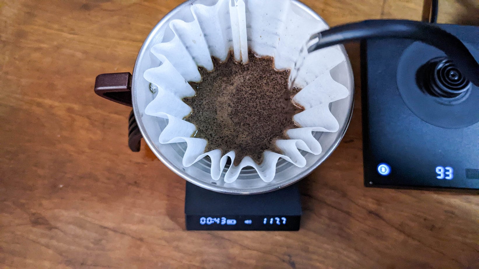 pouring water into brewed coffee grounds in a pour over