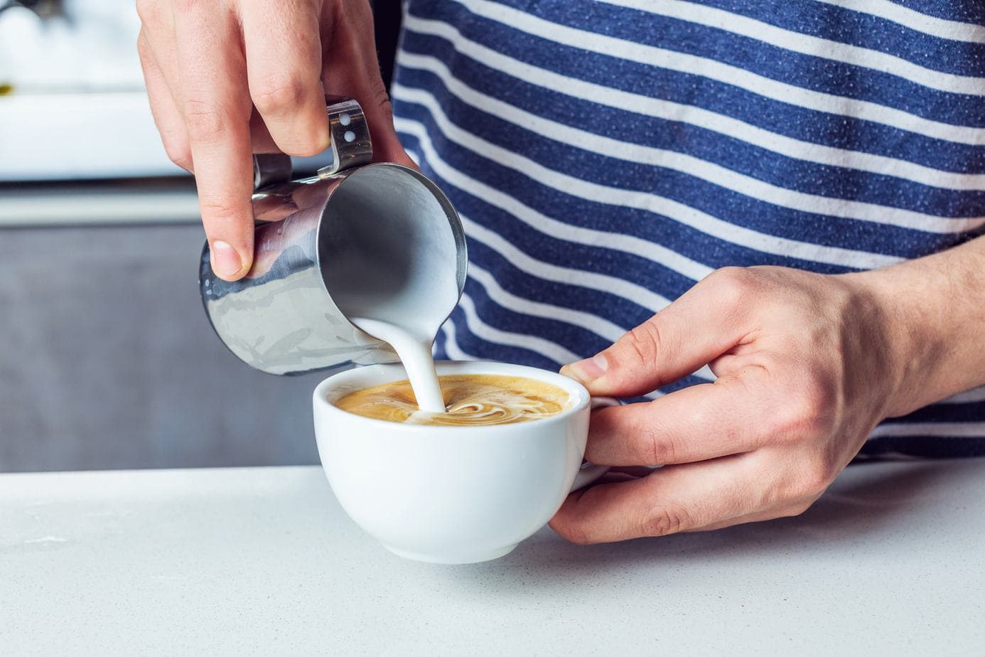 pouring milk in cup of coffee
