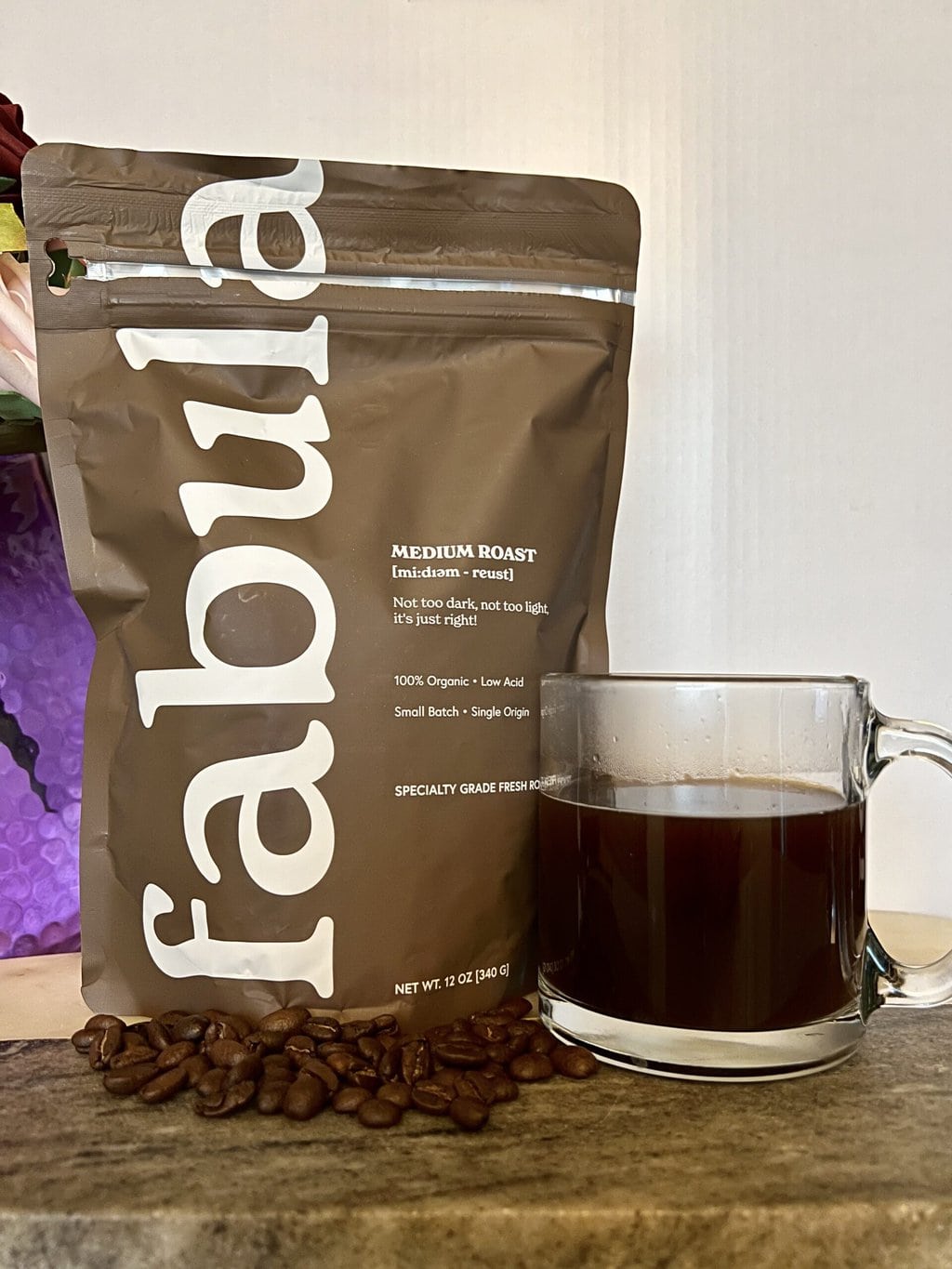Fabula Coffee pack with scattered coffee beans next to a mug of coffee