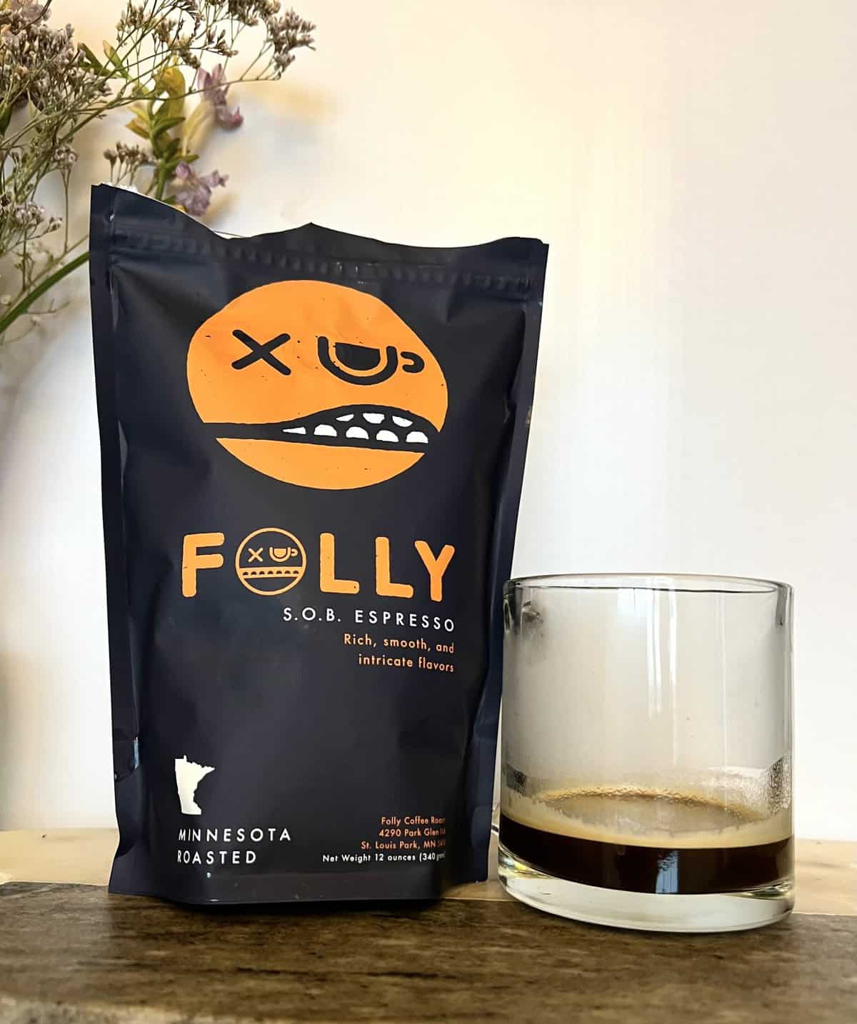 Folly Coffee Subscription Review: Quality Roasted Coffee 15 S.O.B. Espresso Folly coffee pack next to the cup of coffee