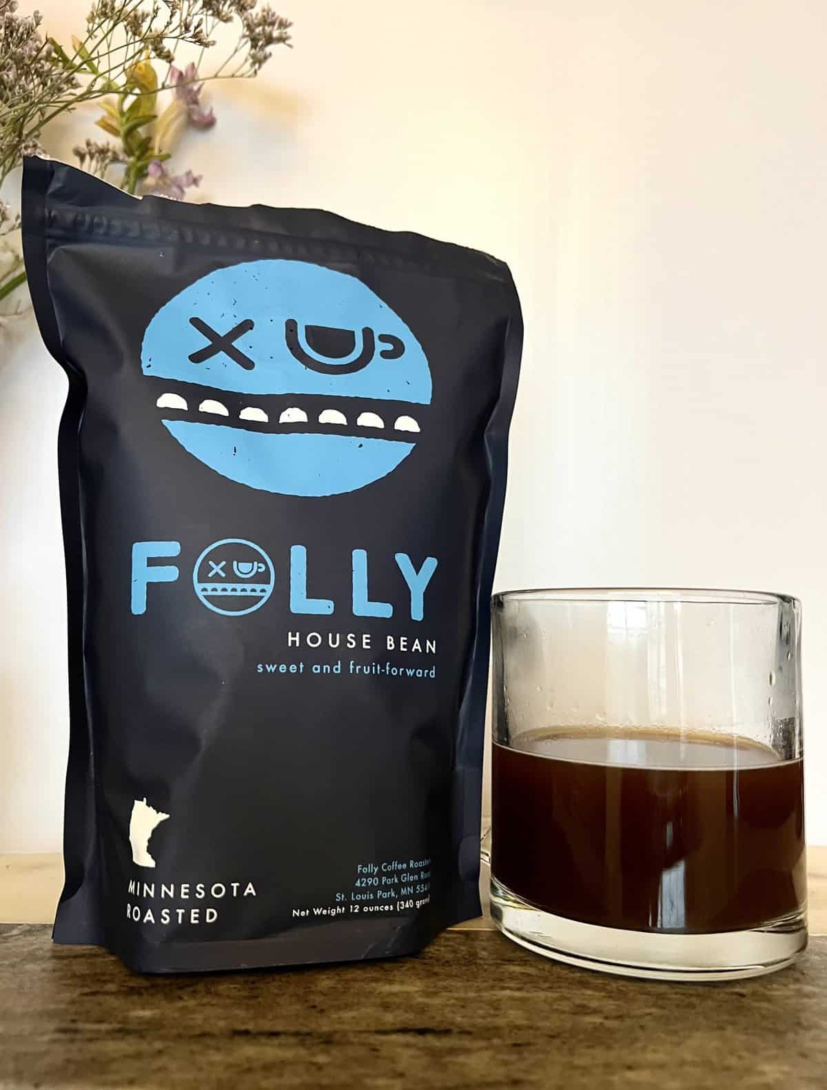 Folly Coffee Subscription Review: Quality Roasted Coffee 10 House Bean Folly Coffee pack next to the cup of coffee