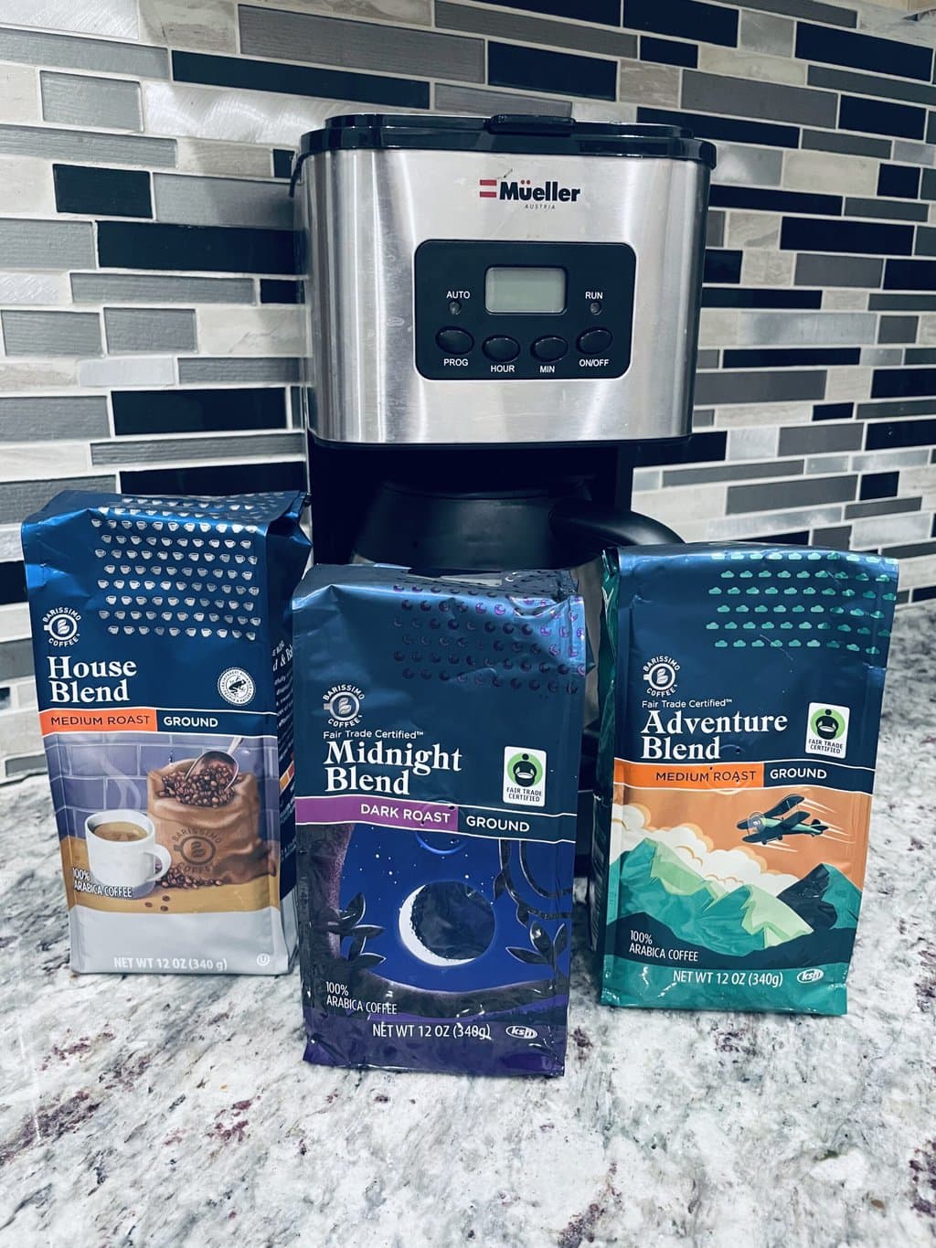 three different coffee packs from Aldi in front of the Mueller coffee maker 