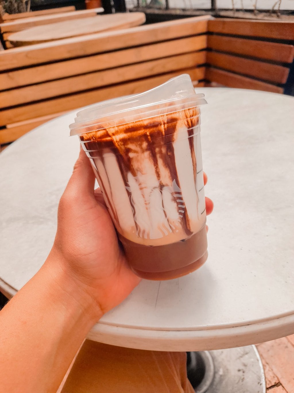Person Holding clear Starbucks Cup with chocolate milkshake drink Starbucks