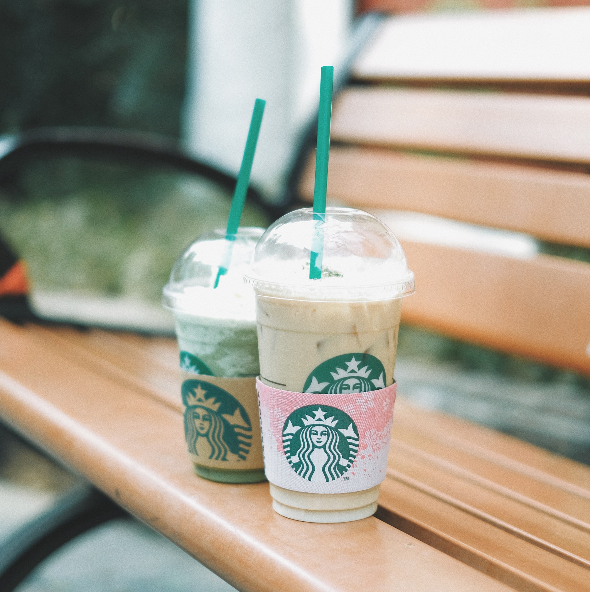 two plastic glasses with Starbucks Green Vanilla Frappuccino on the bench outdoor 