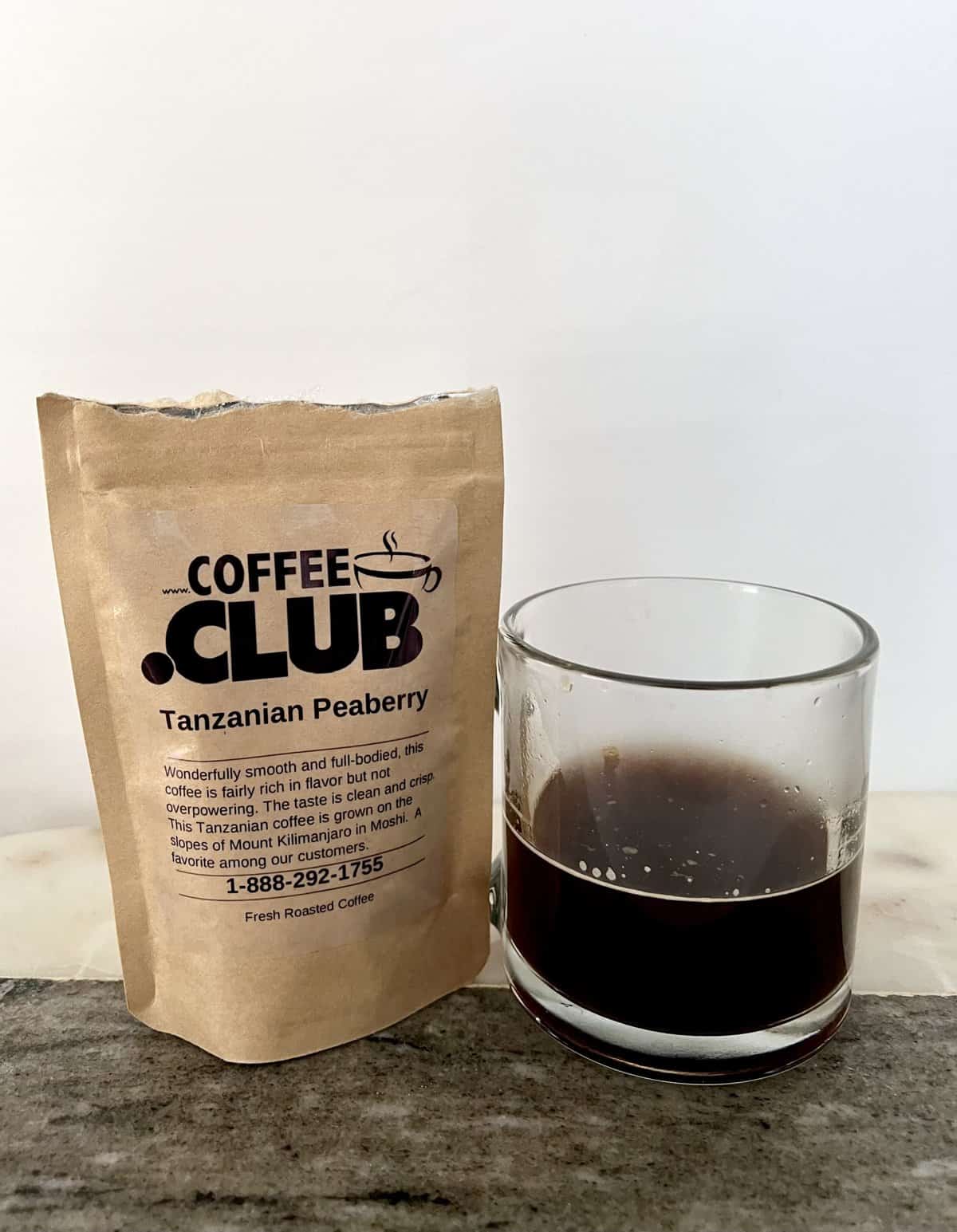 Tanzanian-Peaberry-coffee-next-to-a-cup-of-brewed-coffee-scaled