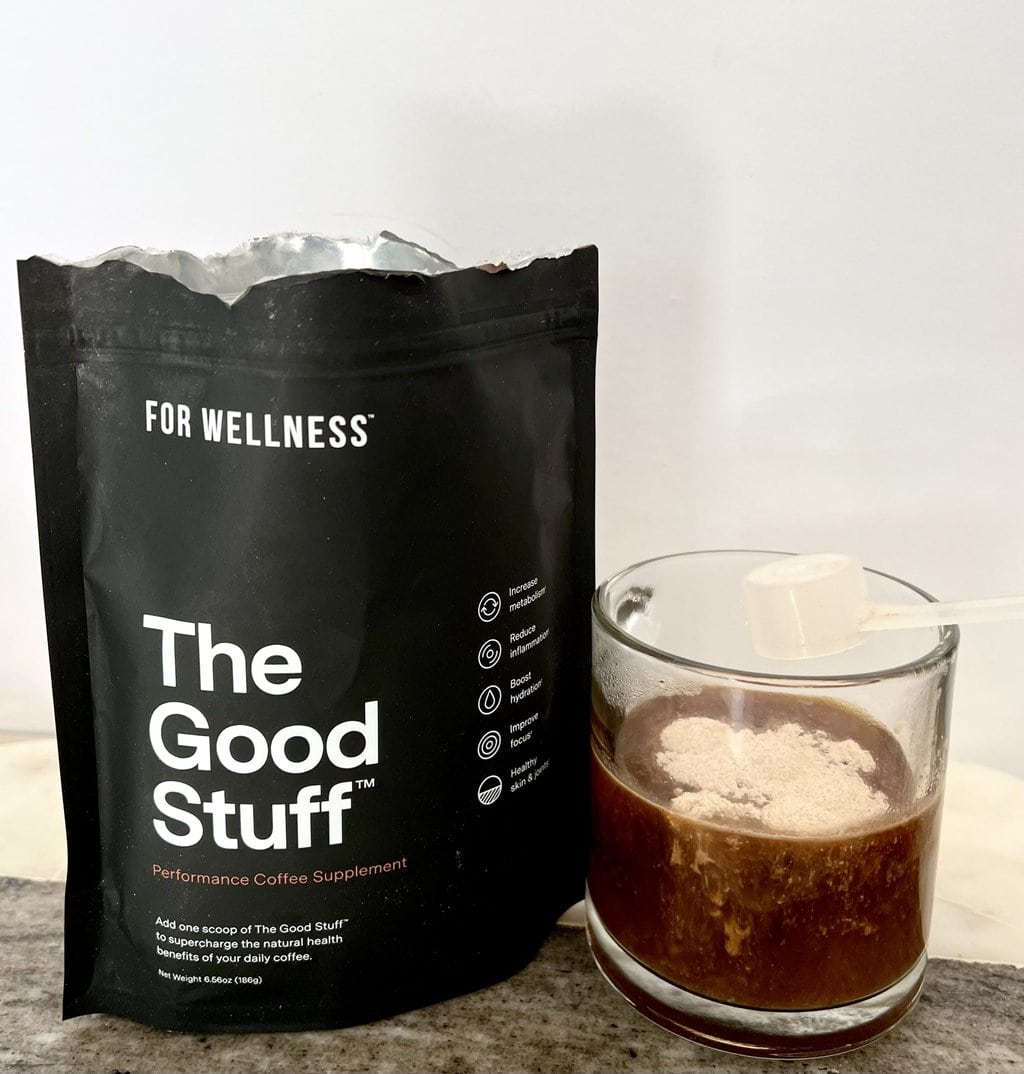 For Wellness The Good Stuff package of coffee additives stands next to a brewed cup of coffee