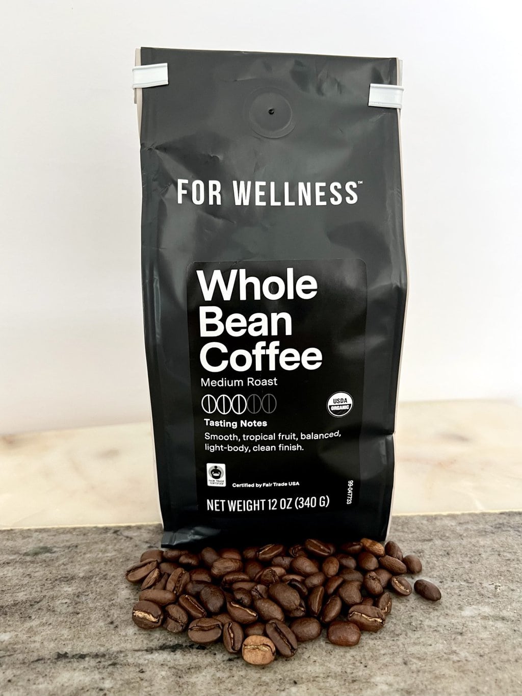For Wellness Whole Bean Coffee Medium Roast Coffee package stands on coffee beans 