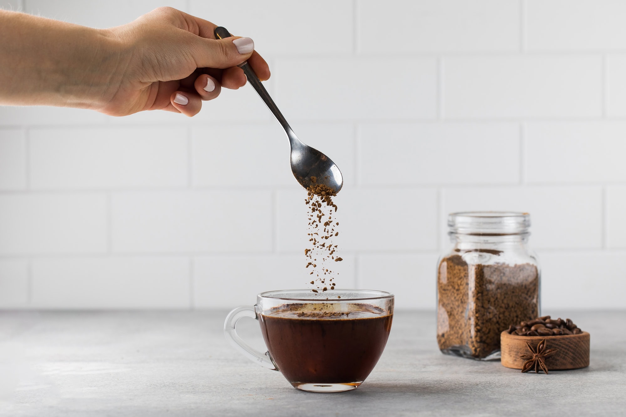 The Best Coffee Brewing Method For Every Zodiac Sign 18 Woman stirs instant coffee in glass mug with boiled water on grey stone table