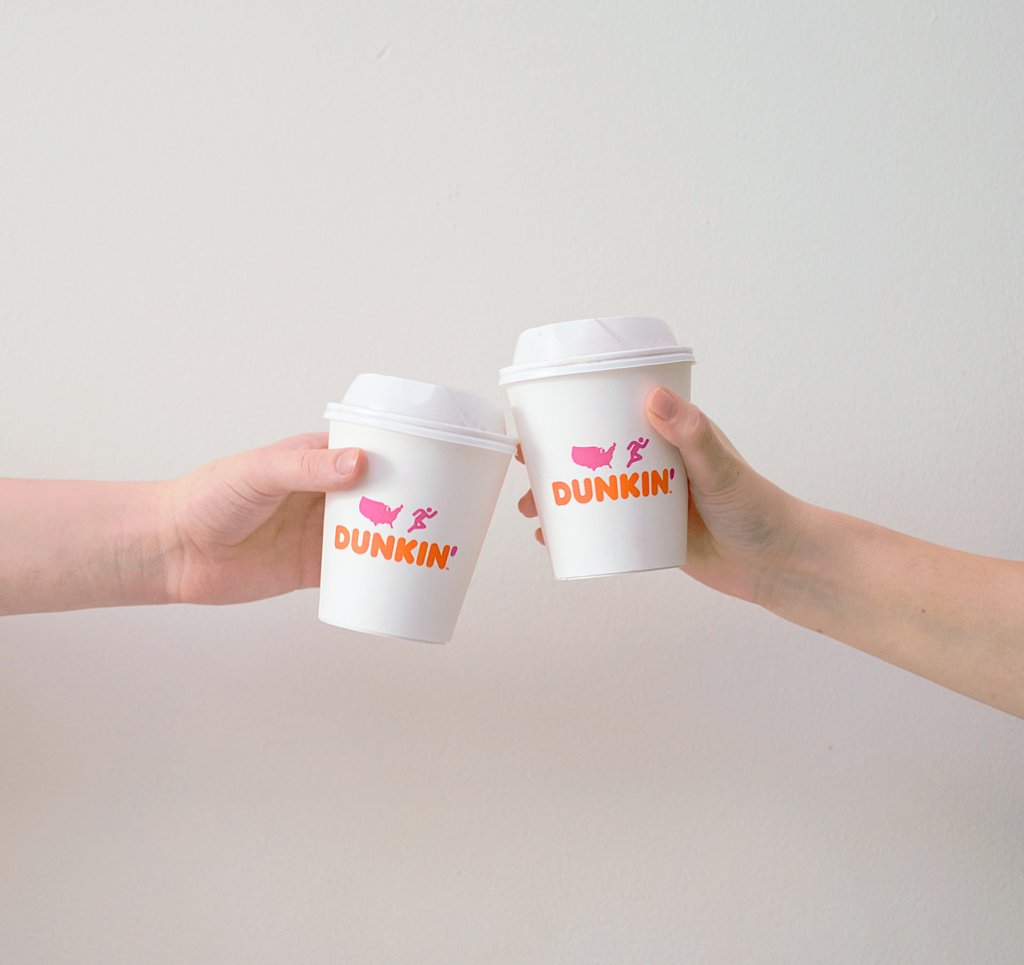 two people cheers their iced drinks at dunkin