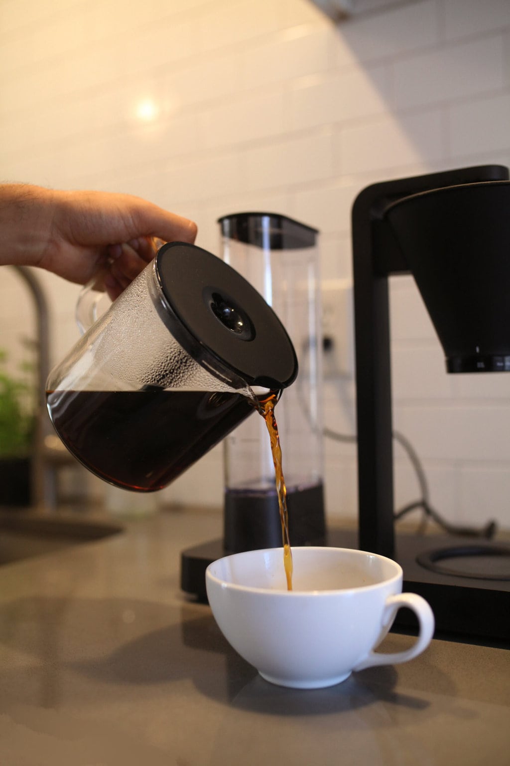 man pouring coffee into a white cup from Wilfa Coffee Maker carafe