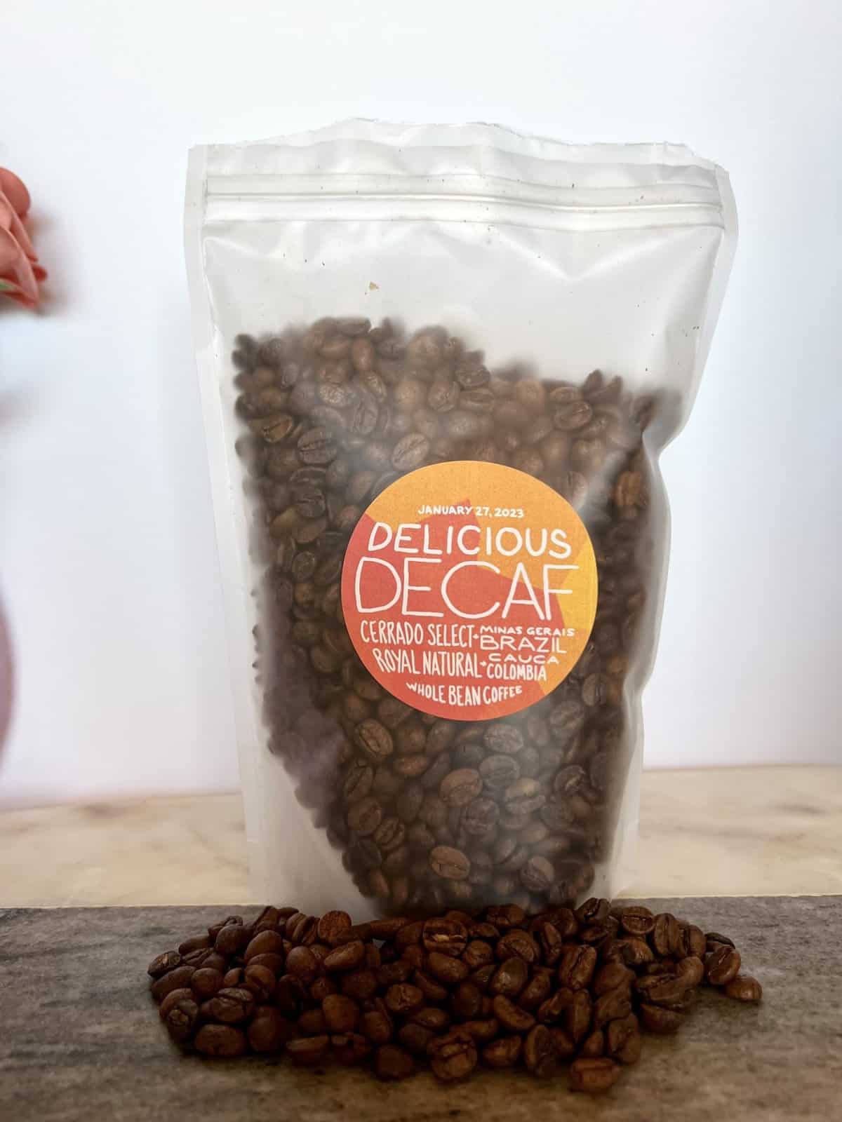 Yes Plz Coffee Review: Roasting Outside The Box 19 Yes Plz packaging of Delicious Decaf Cerrado Select and Royal Natural coffee stands on coffee beans