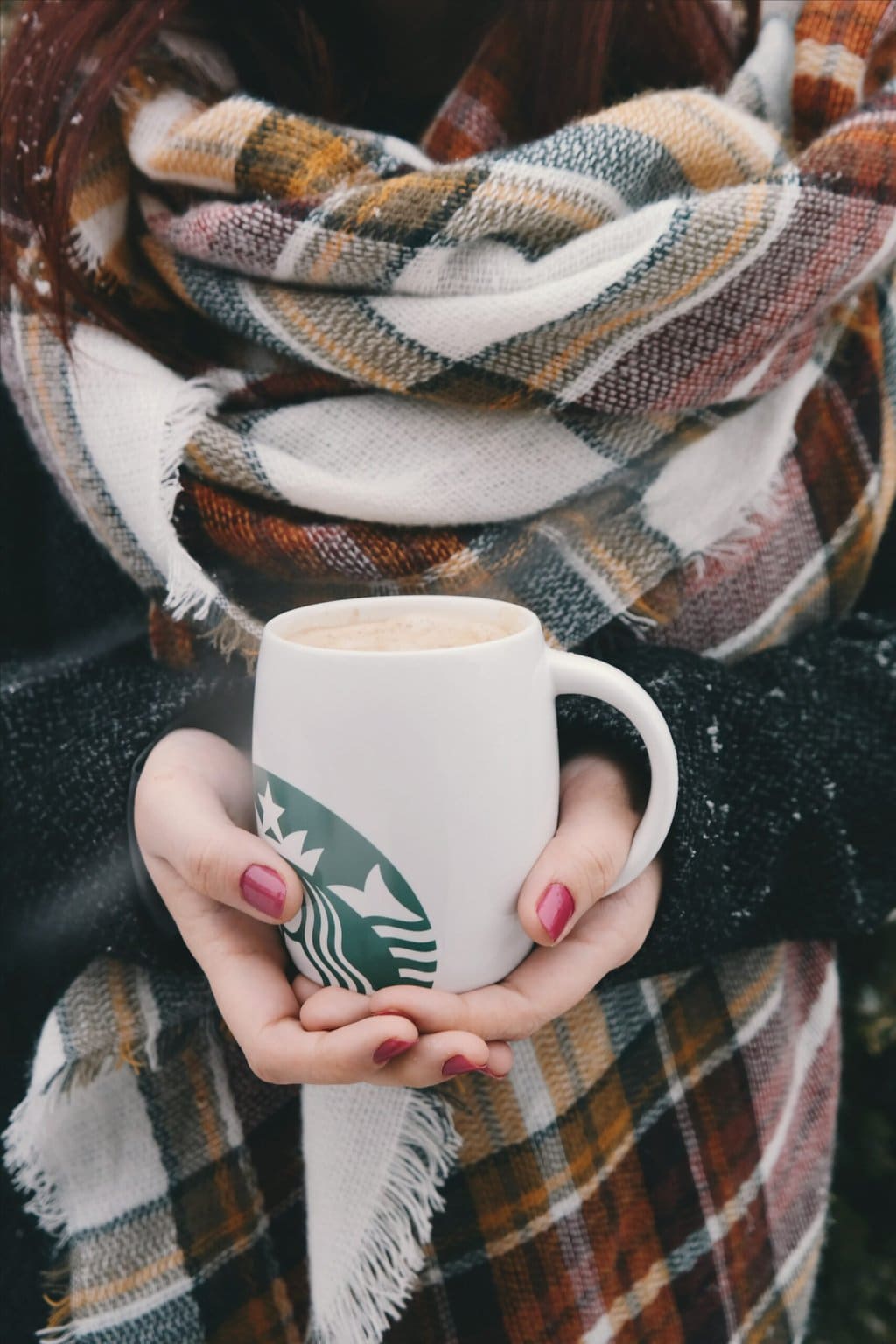 woman holding Starbucks mug with hot drink
