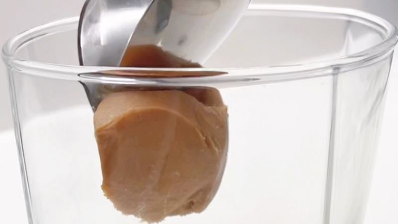 putting a tablespoon of creamy peanut butter into a glass